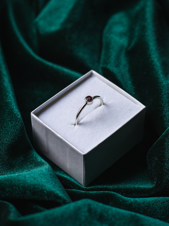 Sormus punaisella kivellä