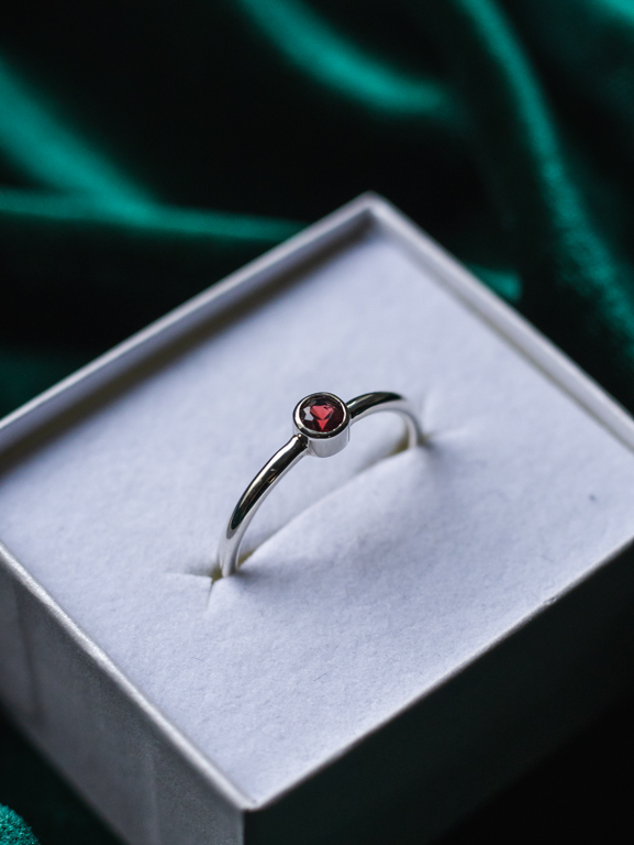 Sormus punaisella kivellä